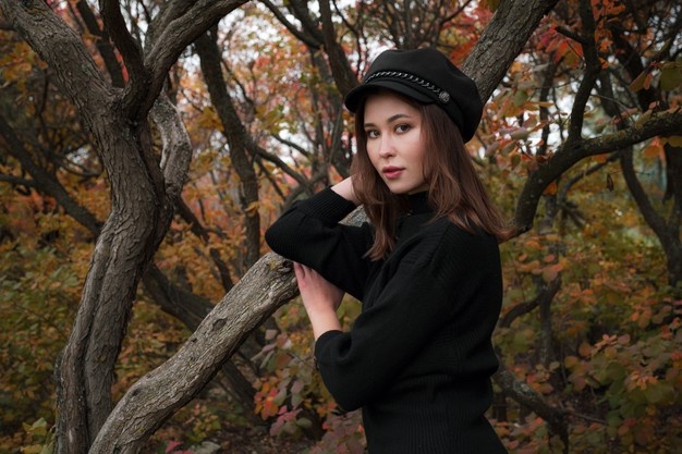 Симпатичная азиатская женщина в хорошем настроении позирует в осенний день, наслаждаясь хорошей погодой. искусство работы романтической женщины. довольно мягкая модель смотрится в камеру.